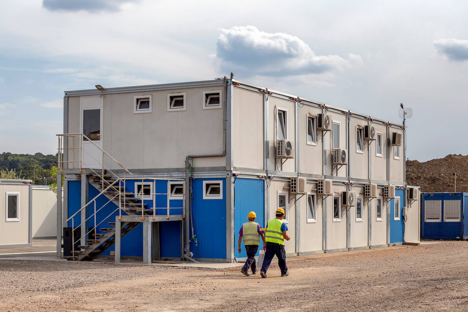 Workers at mobile containers and cabins base for the site manager and employees. Construction site work site fast build mobile prefabricated container houses.